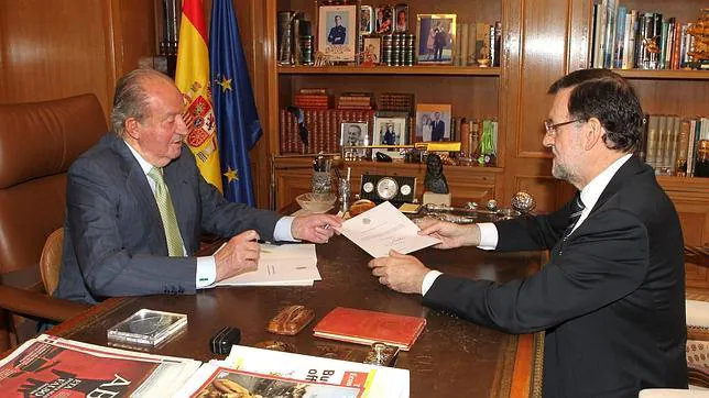 Don Juan Carlos firma ante Rajoy el documento en el que comunica su deseo de abdicar.