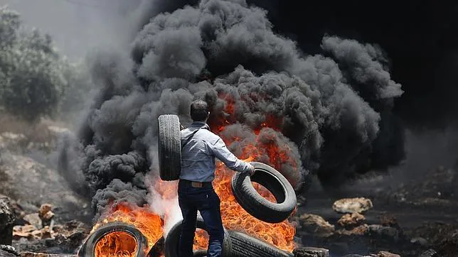 Un manifestante palestino lanza neumáticos al fuego durante los últimos choques contra fuerzas israelíes en un asentamiento de West Bank