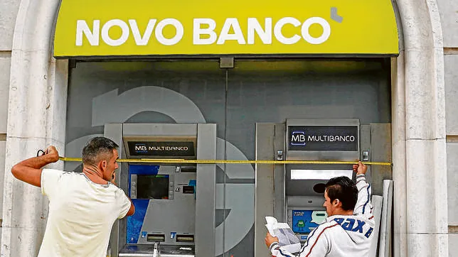 Dos trabajadores colocan el nuevo logo del banco portugués