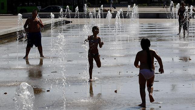 Unos niños se refugian en unas instalaciones de chorros de agua en un parque de Córdoba