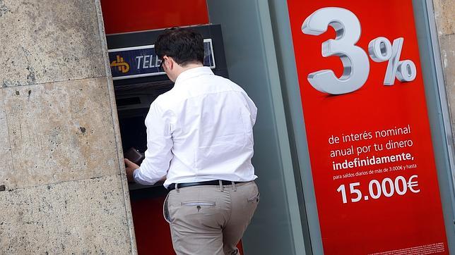 Un hombre retira dinero de un cajero en el centro de Valencia