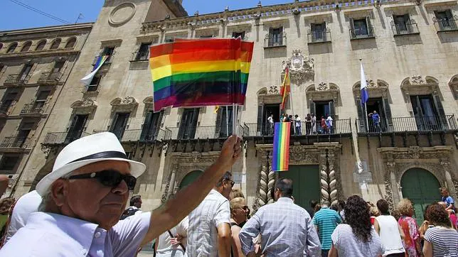 Un hombre enarbola la bandera del orgullo frente al Ayuntamiento