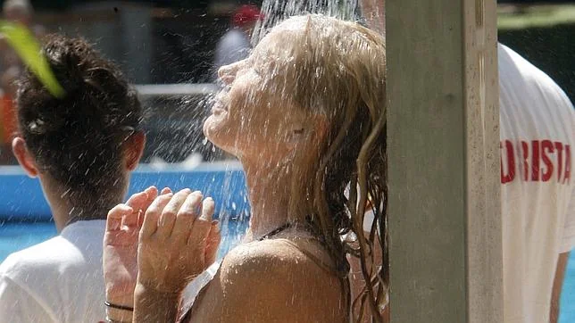 Una chica se ducha en los instantes previos a darse un chapuzón en la piscina municipal de Casa de Campo