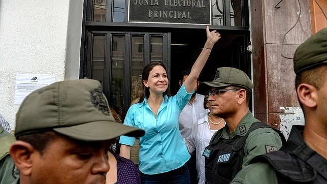 María Corina Machado, rodeada por las fuerzas del orden, saluda a sus simpatizantes a la salida de la Junta Electoral en Los Teques