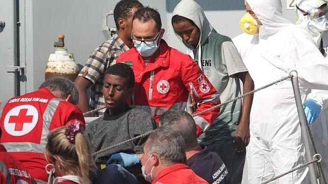 Miembros de la Cruz Roja asisten varios de los 373 rescatados en el naufragio de ayer en las costas libias a bordo del barco de la Marina irlandesa "Lé Niamh" a su llegada al puerto de Palermo