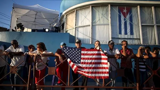 Un hombre sostiene una bandera de EE.UU. junto a la recién reabierta Embajada de ese país en La Habana