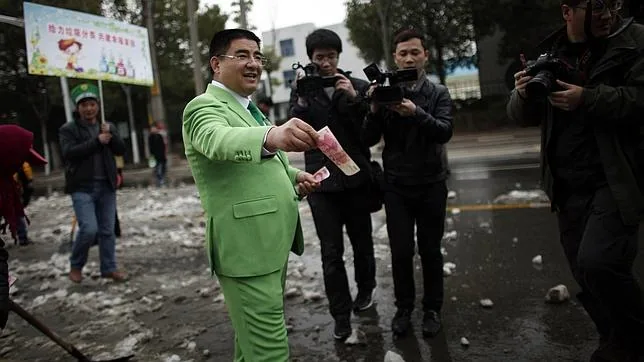 El millonario chino Chen Guangbiao ofrece dinero a los barrenderos durante una campaña para la limpieza de las calles en 2013