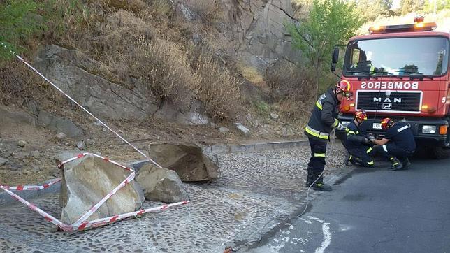 Los bomberos retiran grandes rocas caídas sobre la carretera del Valle