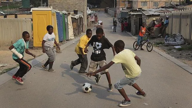 Un grupo de niños disputa un partido de fútbol después del colegio en un descampado de Johannesburgo (Sudáfrica)