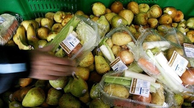 Un cluente coge una cesta de verduras en un supermercado