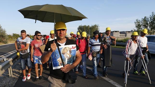 Refugiados caminan con una foto de Merkel este viernes a las afueras de Budapest hacia la frontera con Austria