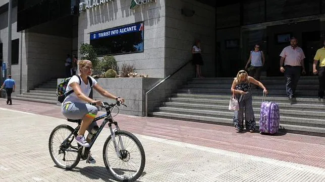 Una ciclista transita junto a la estación de tren de Alicante