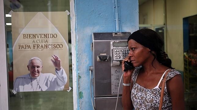Una mujer habla por teléfono junto a un cartel con la imagen del papa Francisco, en La Habana (Cuba)