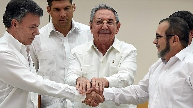 El presidente de Colombia, Juan Manuel Santos, estrecha la mano del líder de las FARC, «Timochenko», del presidente de Cuba