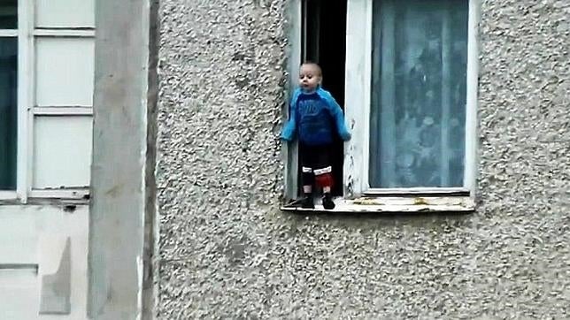 Un niño ruso se juega la vida en el borde de una ventana de un octavo piso