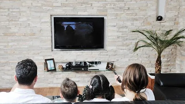 Una familia mira la televisión en el salón de su casa