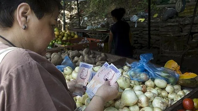Una venezolana paga su compra con bolívares en un mercado callejero de Caracas