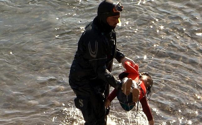 Un miembro de la Guardia Costera saca del agua el cuerpo de una niña refugiada hallada en la costa de Lesbos