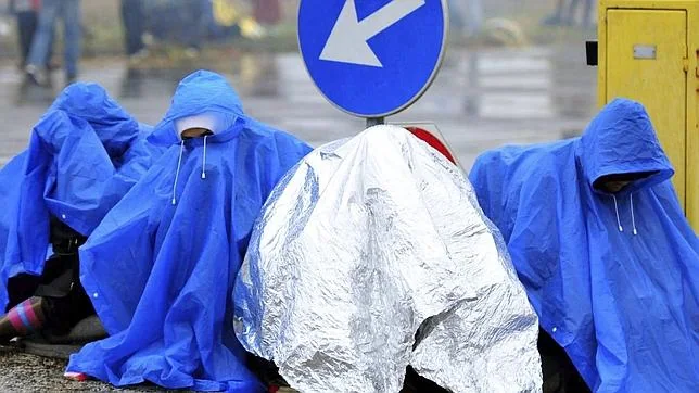 Un grupo de refugiados espera bajo la lluvia en la frontera entre Croacia y Eslovenia