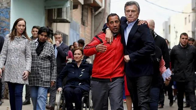 Mauricio Macri (d) abraza a un seguidor durante un acto de campaña en una barriada de Buenos Aires