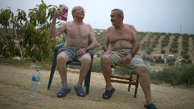 Dos hombres se intentan librar del calor con agua y un abanico improvisado