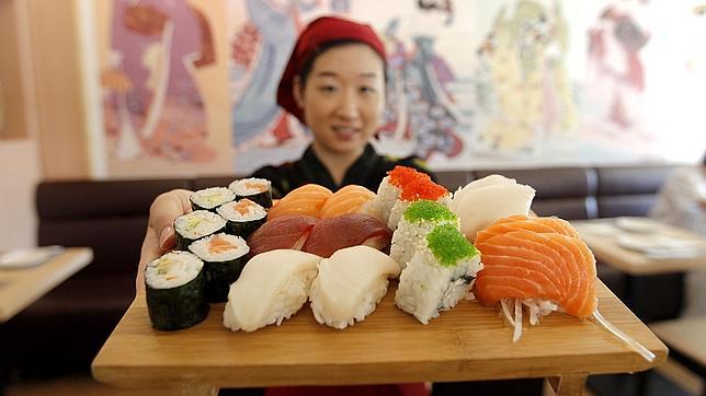 Una camarera de Sushicolor muestra una variada bandeja de sushi