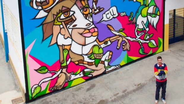 Denis Due junto al mural que ha realizado para el colegio La Alunada