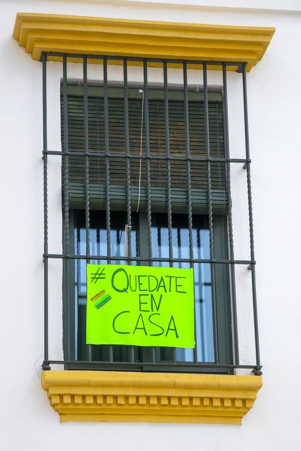 Lunes Santo. El Cautivo (Polígono de San Pablo). Confinamiento de la población tras las puertas y barrotes de las ventanas de sus hogares a causa de la pandemia del coronavirus. El cartel de la vivienda hace un ejercicio de responsabilidad, "#QUEDATE EN CASA"