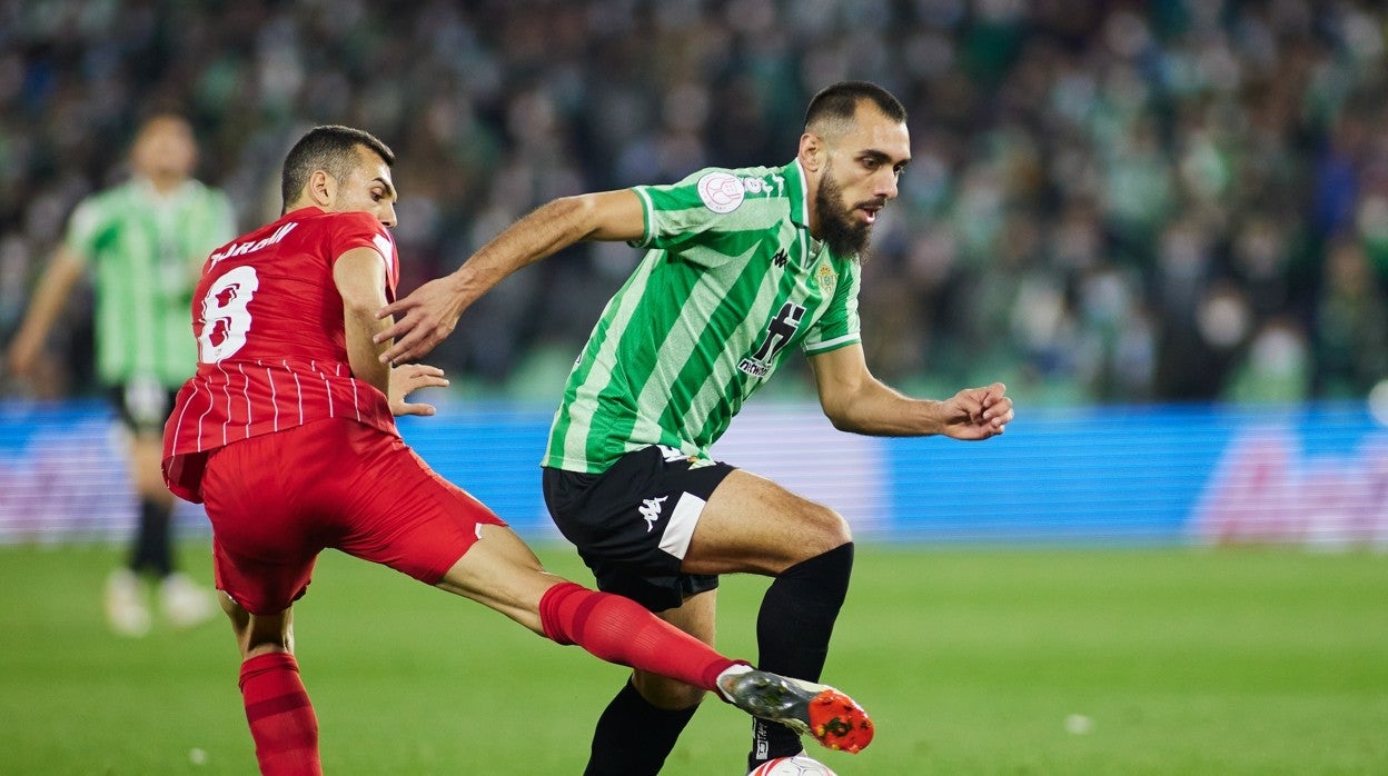 Borja Iglesias avanza ante Joan Jordán durante el derbi Betis - Sevilla de la Copa del Rey