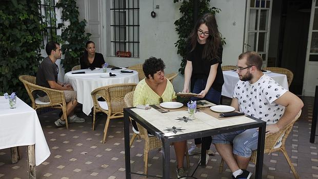 Una joven camarera atiende una mesa en un restaurante de la capital