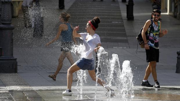 Una joven juega con los chorros de agua de la plaza de las Tendillas de Córdoba