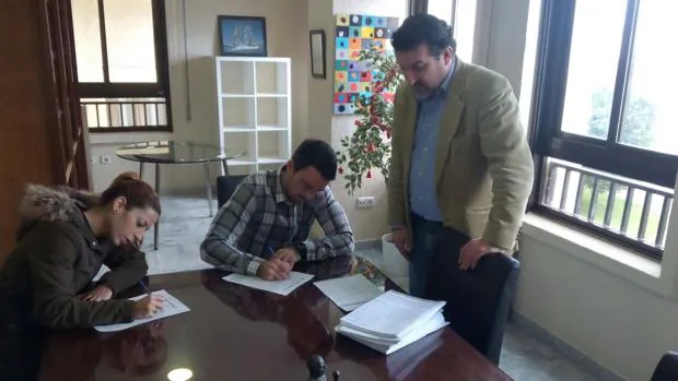 Dos jóvenes estampan sus firmas, en presencia del abogado Manuel Martos, promotor de la iniciativa