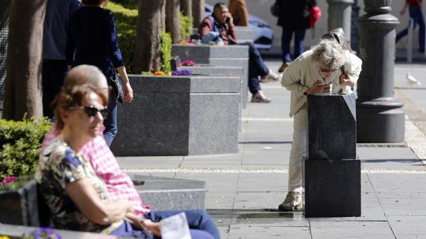 Una señora bebe agua de una de las fuentes de la plaza e Las Tendillas