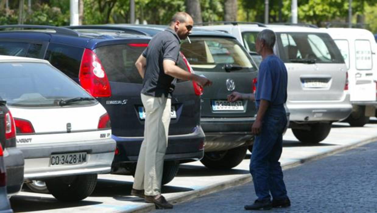 Un hombre pagando a un aparcacoches en la zona de La Victoria