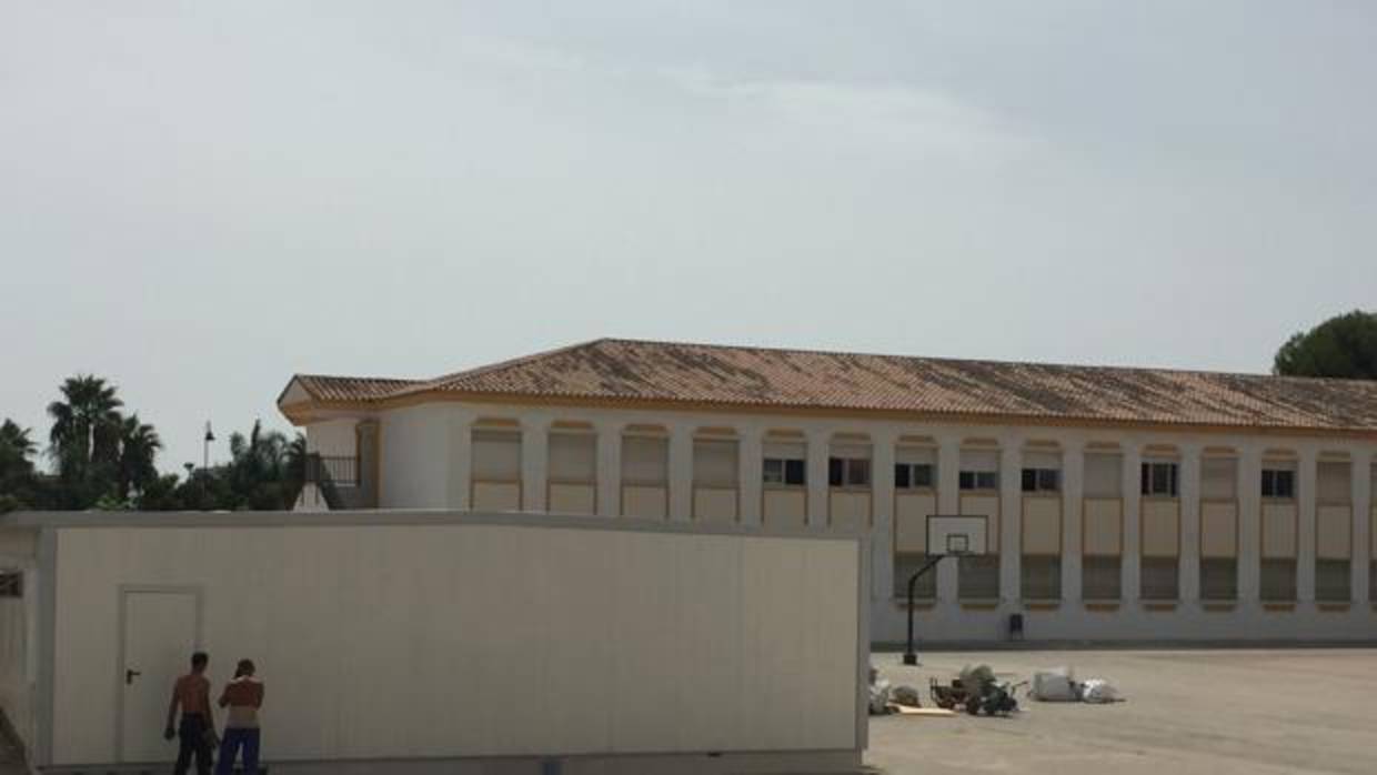 Dos operarios terminan las instalación de la nueva caracola en el patio del colegio