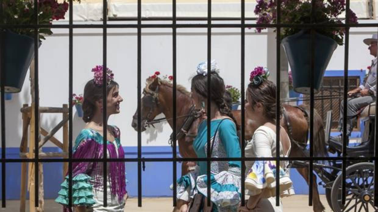 Tres jóvenes vistas a través de una caseta de la Feria de Nuestra Señora de la Salud