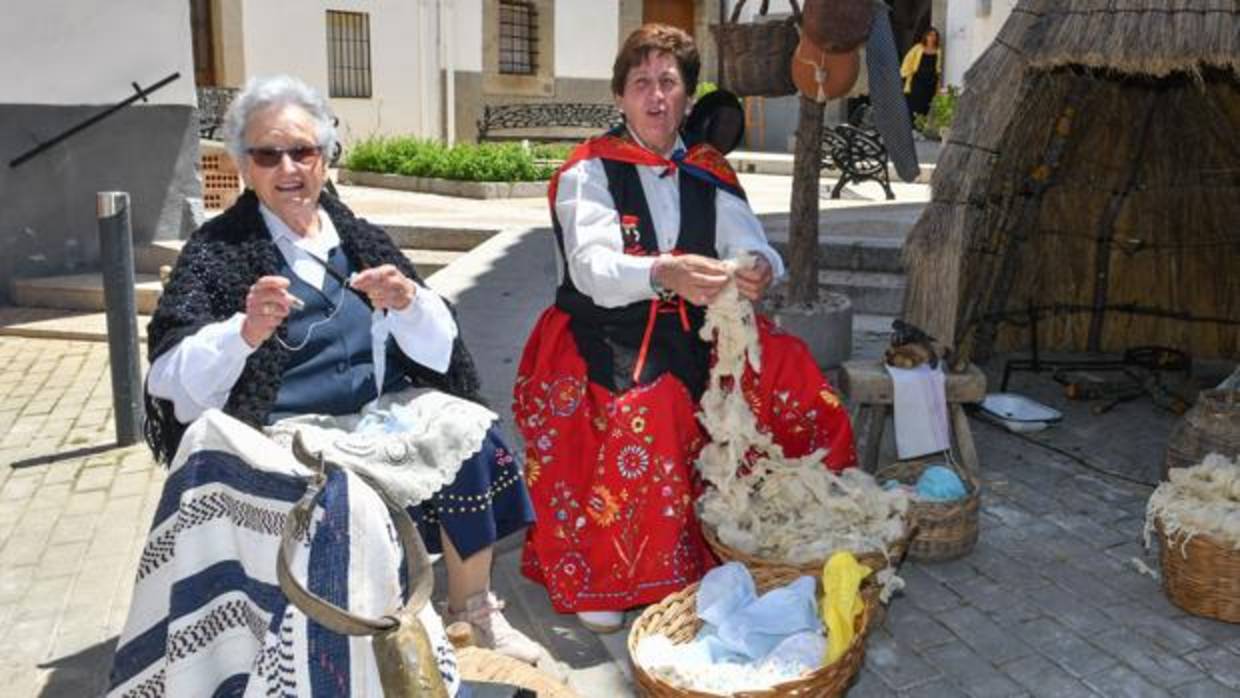 Dos mujeres trenzan lana de oveja en una calle de Villaralto