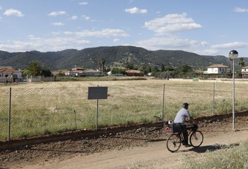 Un hombre con una bicicleta en una parcelación colindante al monumento