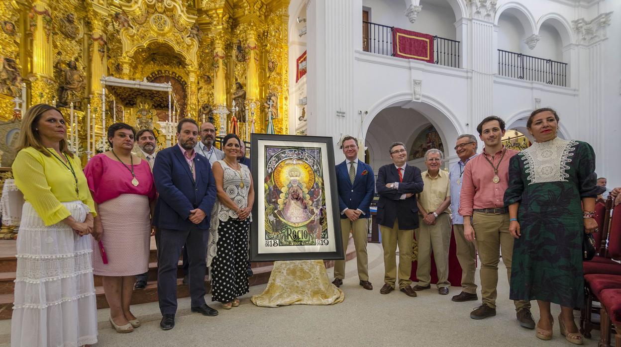 La Junta de Gobierno de la Matriz almonteña posa junto al cartel anunciador del Centenario. Juan Miguel Martín Mena, autor de la obra, primero a la derecha del cartel