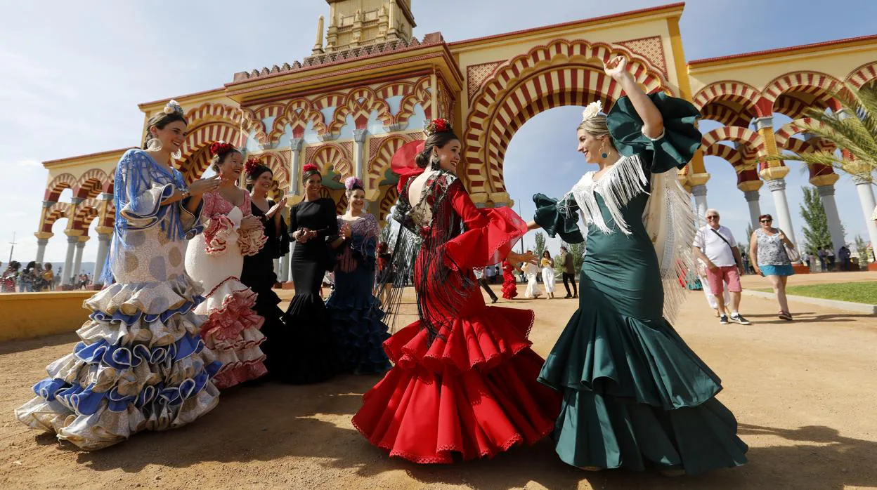 Dos jóvenes bailan ante la portada de la Feria de Córdoba