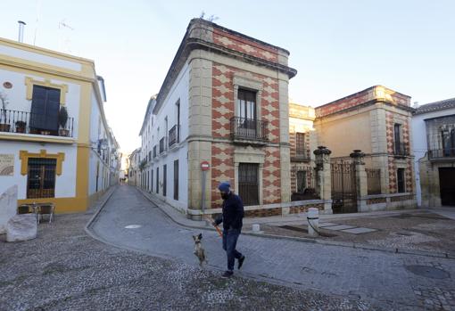Un hombre pasea a su perro delante del Palacete de los Burgos