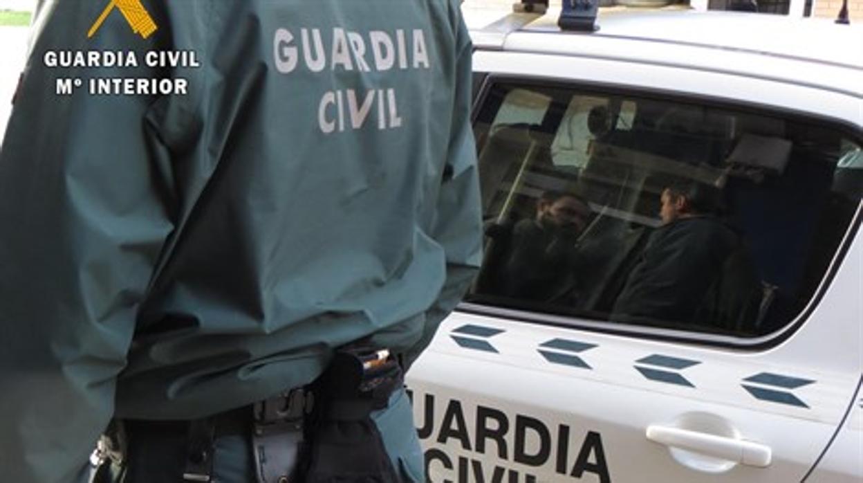 Un agente de la Guardia Civil, junto a un vehículo policial en una imagen de archivo.