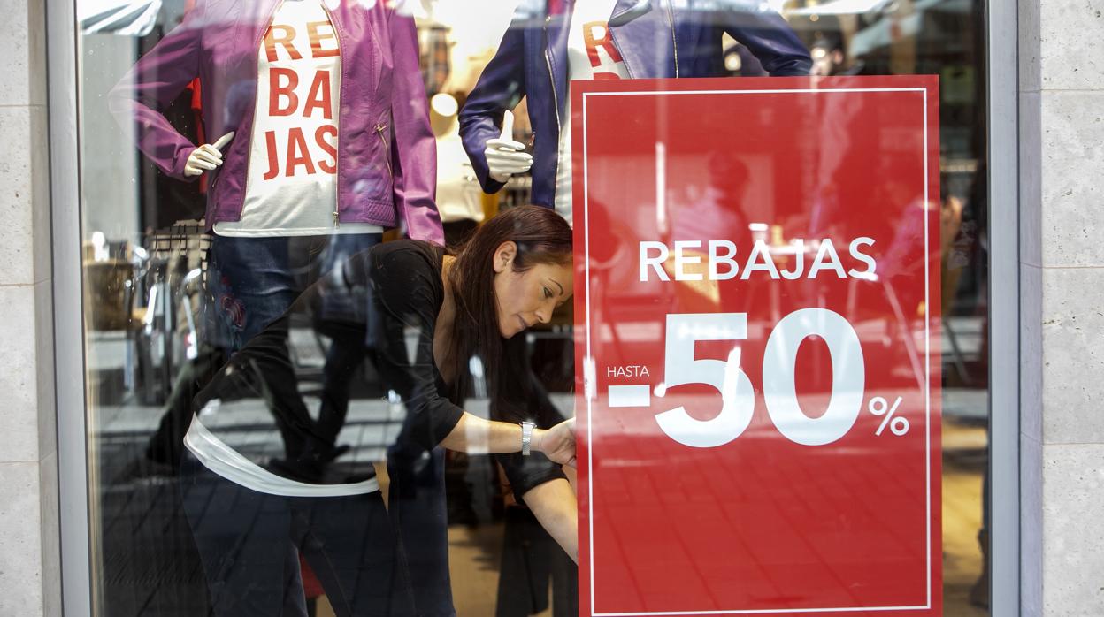 Una trabajadora de una tienda del Centro, el sábado colocando un cartel de rebajas