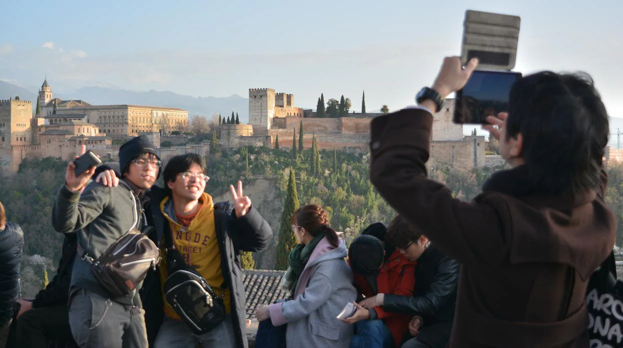Turistas se fotografían frente a la Alhambra en el Mirador de San Nicolás.
