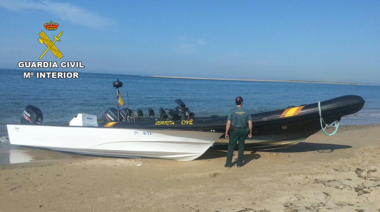 Un agente junto a una narcolancha en una playa de Huelva
