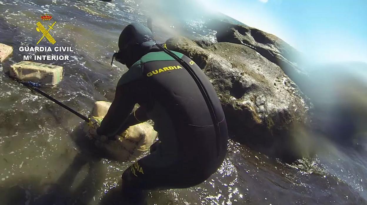 Un buzo de la Guardia Civil saca del mar fardos de hachís
