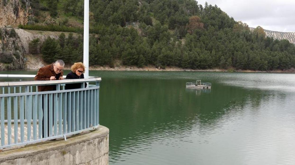 Dos personas se asoman al pantano de Iznájar, casi al borde de su capacidad
