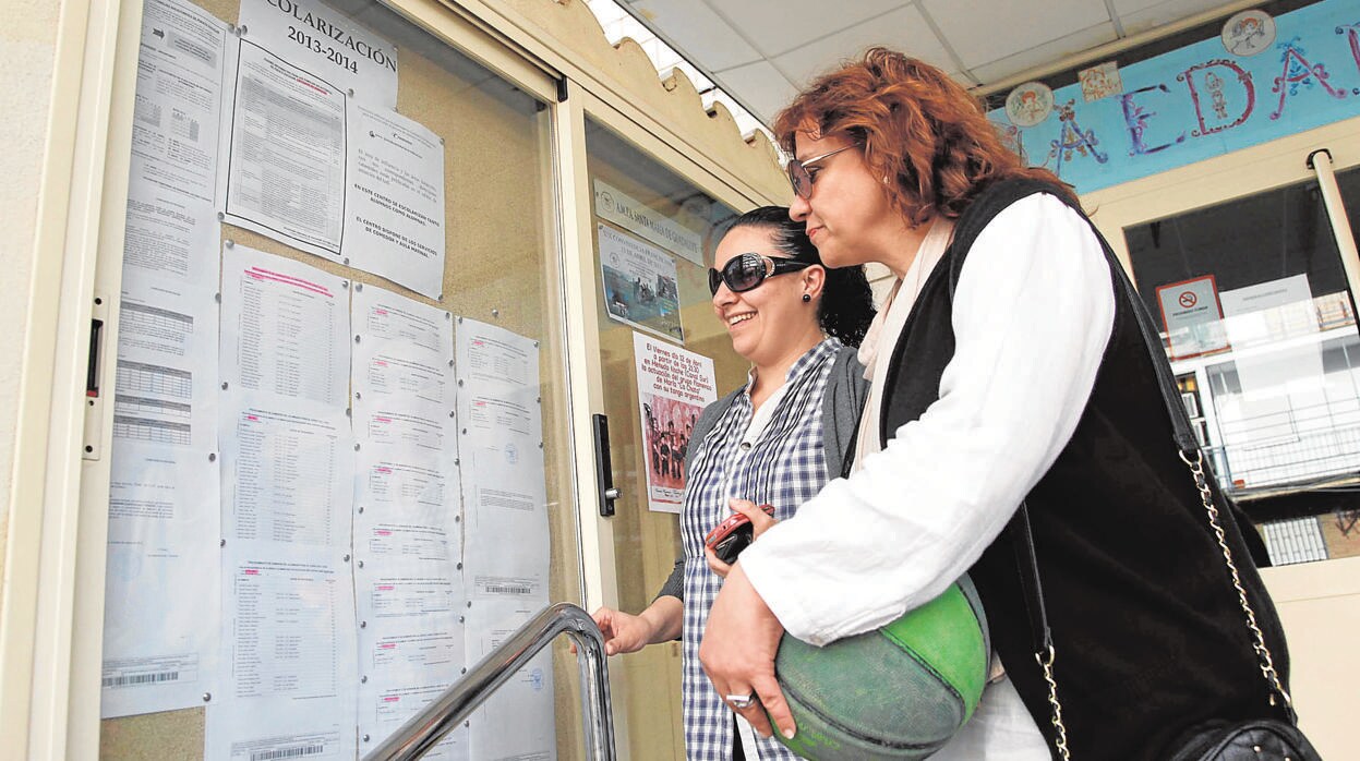 Dos madres consultan la lista de escolarización en un colegio del Centro