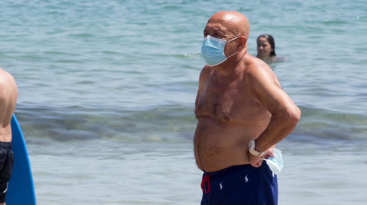 Un hombre con mascarilla a la orilla del mar