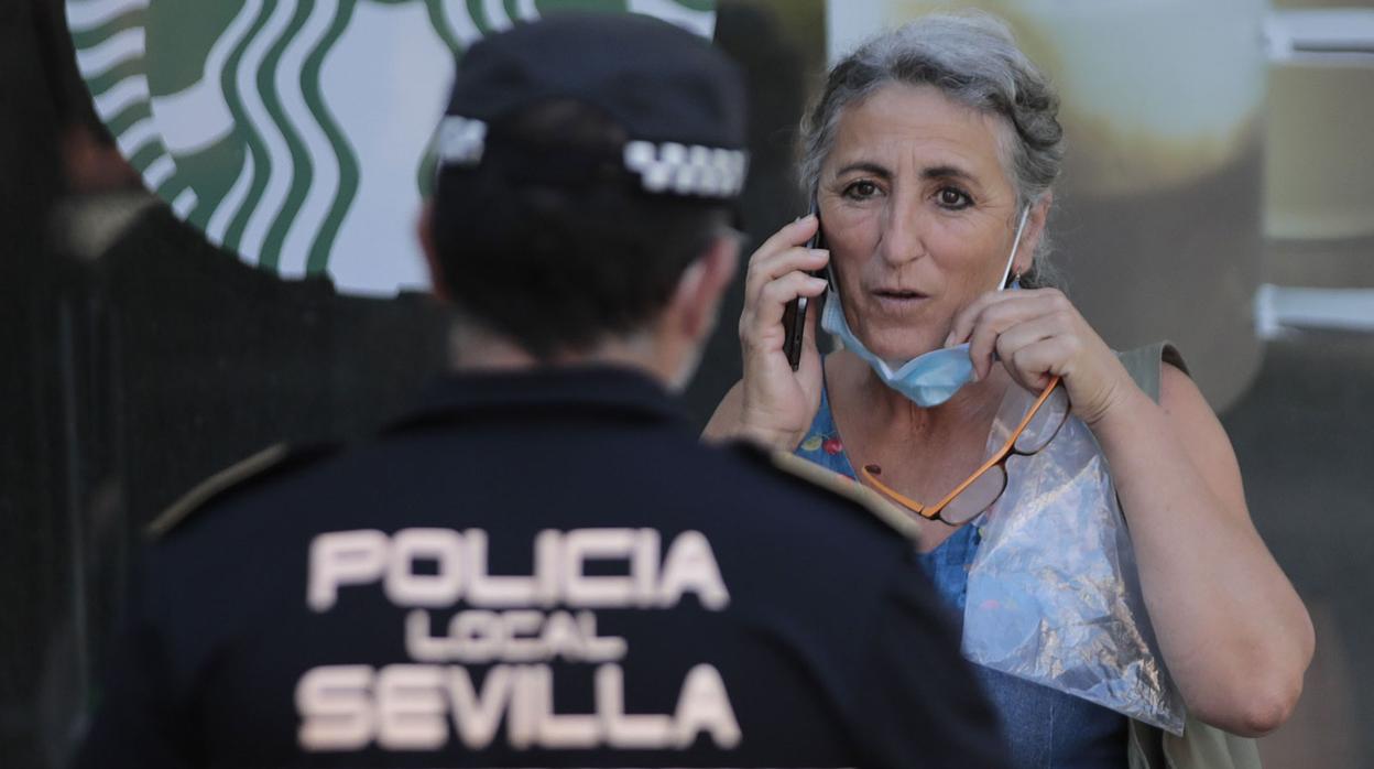 Un agente de la Policía Local de Sevilla junto a una mujer sinla mascarilla puesta
